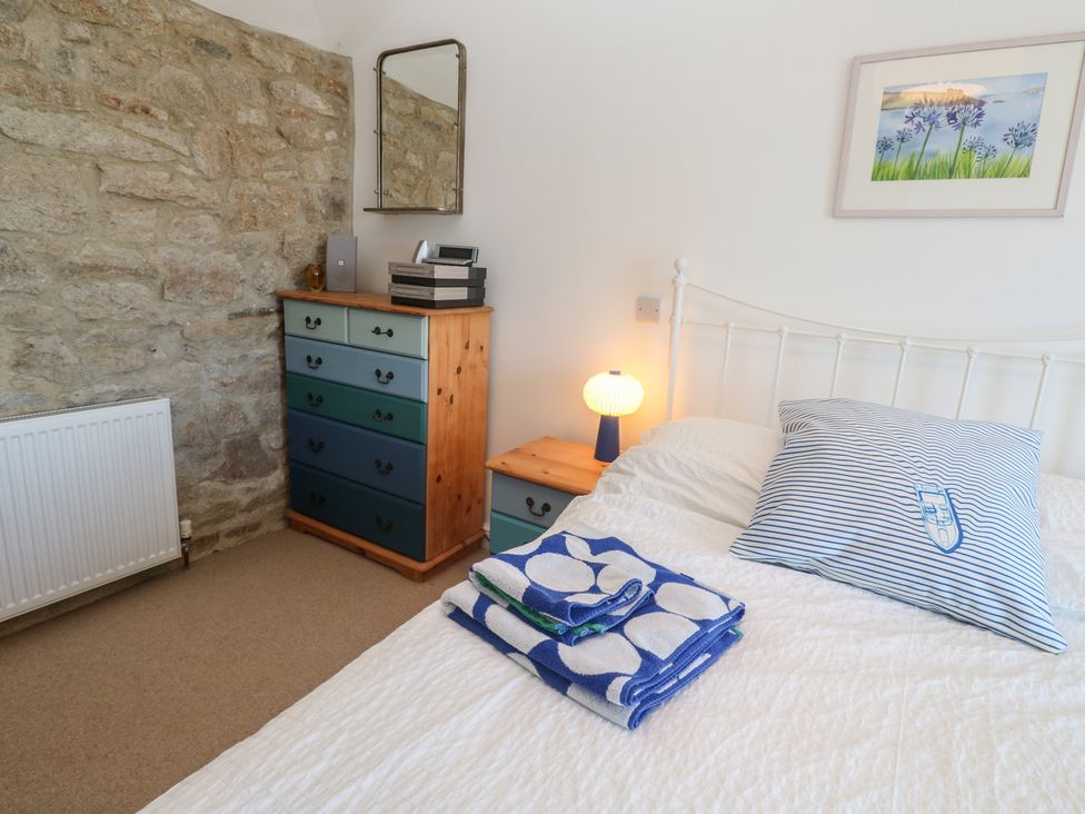 A bedroom with a bed and a dressing table at 12 Boswedden Terrace St Just