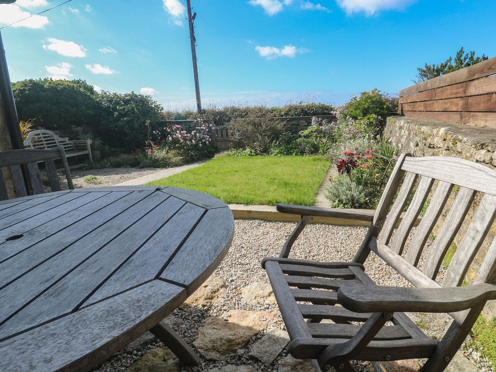 A garden with a wooden table and chair at 12 Boswedden Terrace St Just