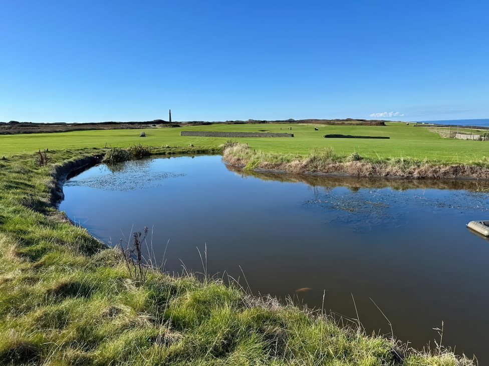 A golf course with a pond and lighthouse at Sea Holly in St Just