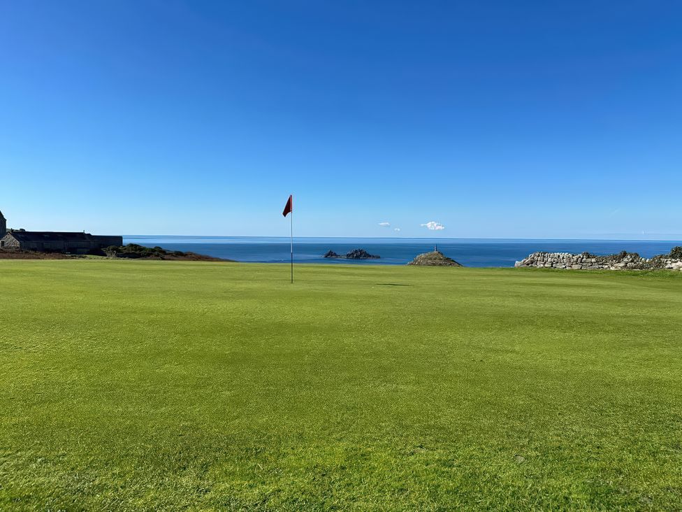 A golf course with a flag and ocean view at Sea Holly, St Just
