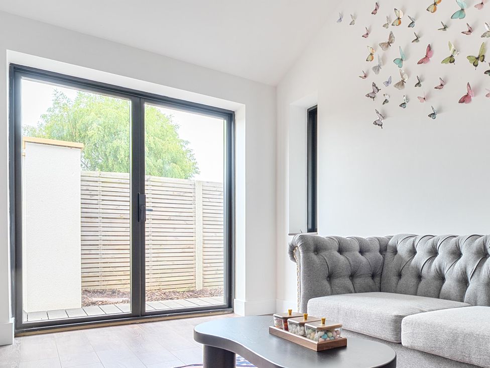 A living room with a grey sofa and sliding doors at Manor Farm House Merton near Bicester