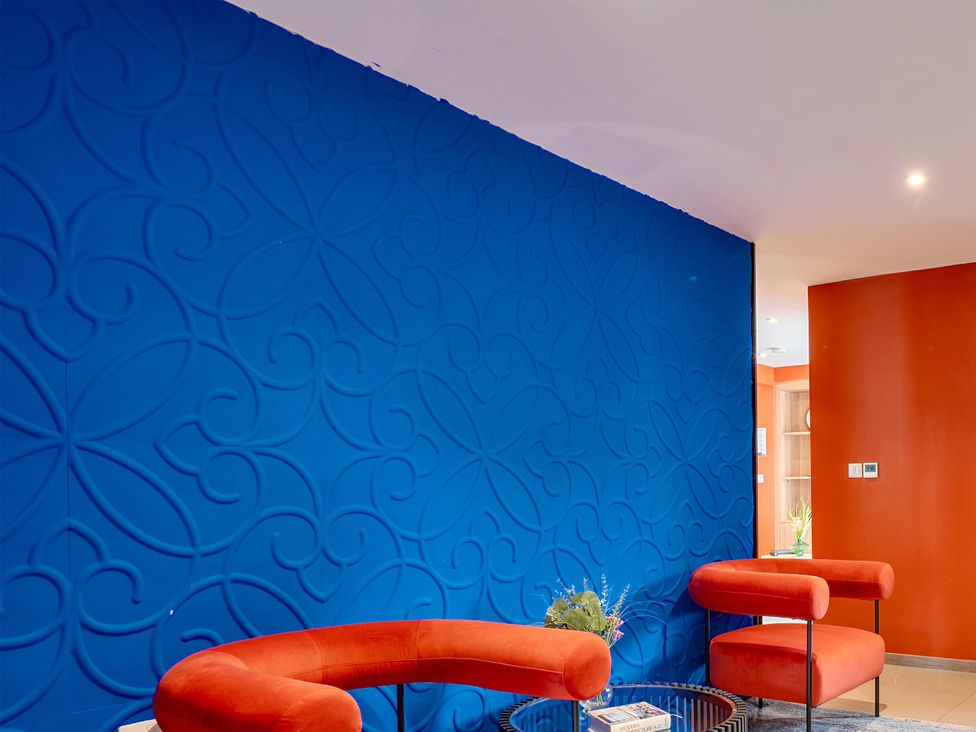A living room with a blue wall and orange wall at Manor Farm House in Merton near Bicester