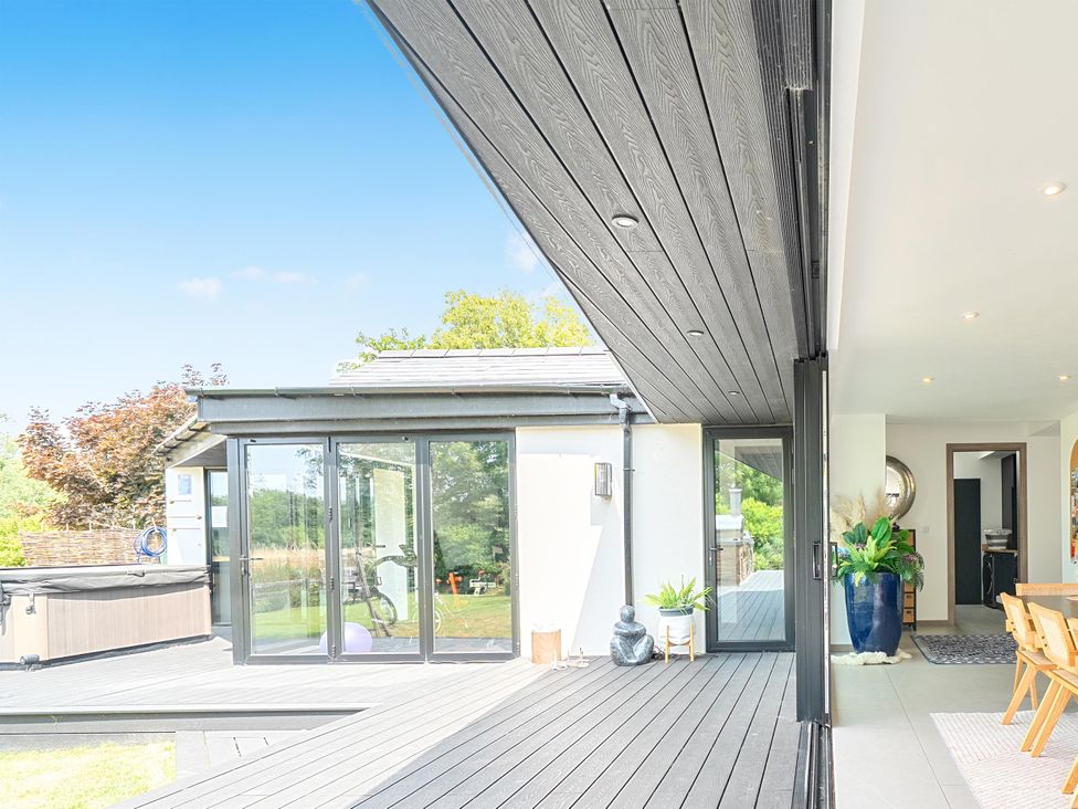 An outdoor area with decking and a hot tub at Manor Farm House in Merton near Bicester