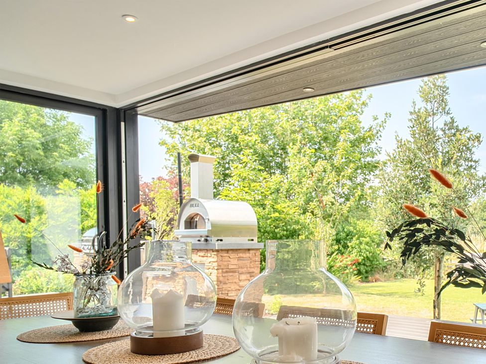 A dining room with vases and a view of an outdoor oven at Manor Farm House in Merton near Bicester