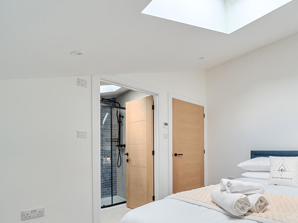 A bedroom with a bed and a shower door at Manor Farm House in Merton near Bicester