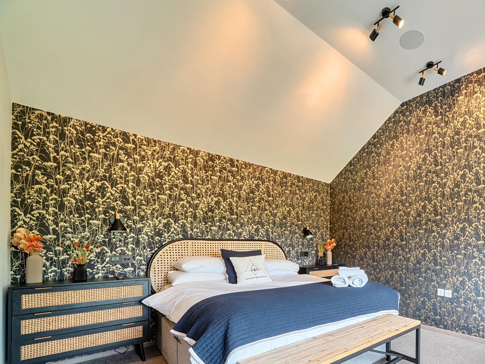 A bedroom with a bed and decorative wall at Manor Farm House in Merton near Bicester