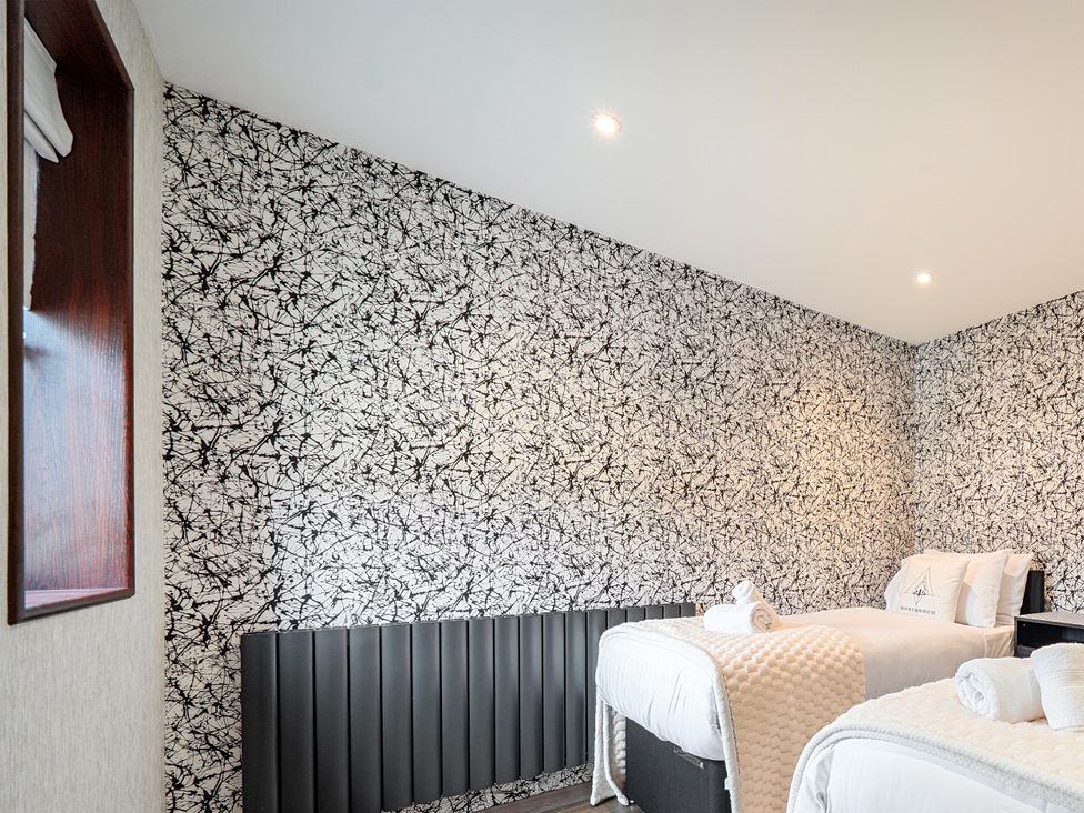 A bedroom with two beds and a decorative wall at Manor Farm House in Merton near Bicester
