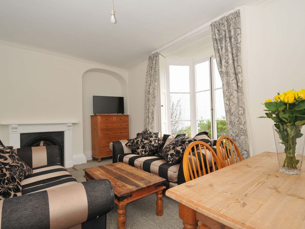 A living room with a sofa, television, and dining table at Violet's Rest in Exeter