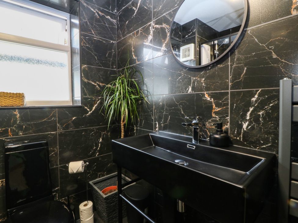 A bathroom with black tiled walls at 61 Lloyd Street West in Llandudno