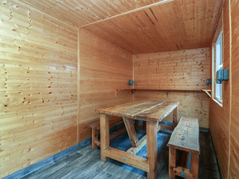 A snug with wooden table and benches at 61 Lloyd Street West in Llandudno