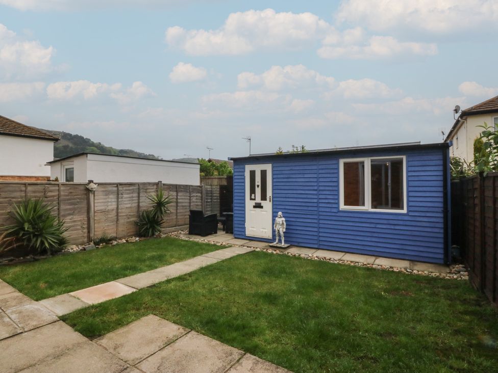 A garden with a blue shed and stone pathway at 61 Lloyd Street West in Llandudno