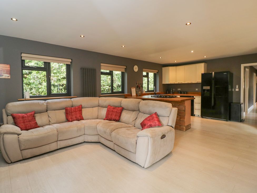 A living room with a sofa and kitchen area at Willow Cottage in Whiteparish