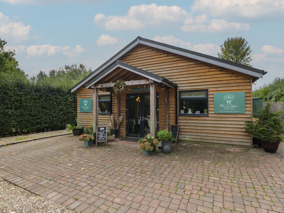 An outdoor view of a wooden building with a sign at Willow Cottage in Whiteparish