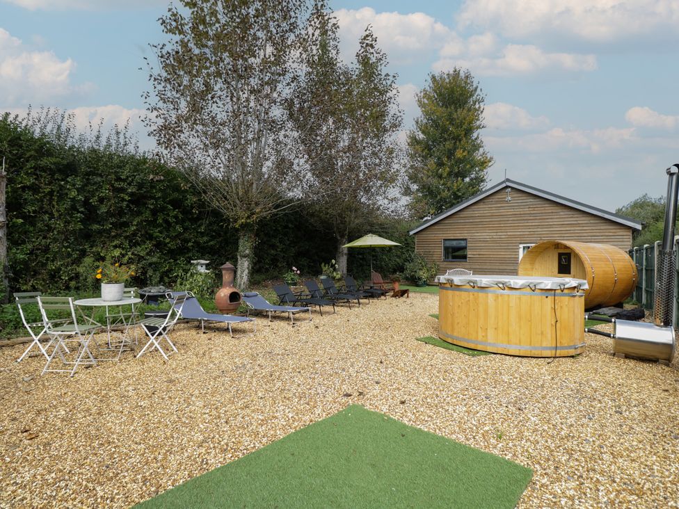 A garden area with lounge chairs and a barrel at Willow Cottage in Whiteparish