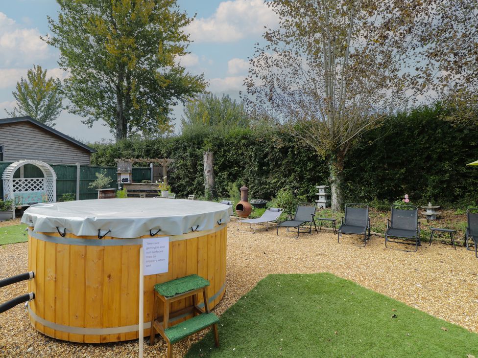 A garden with a hot tub and lounge chairs at Willow Cottage in Whiteparish