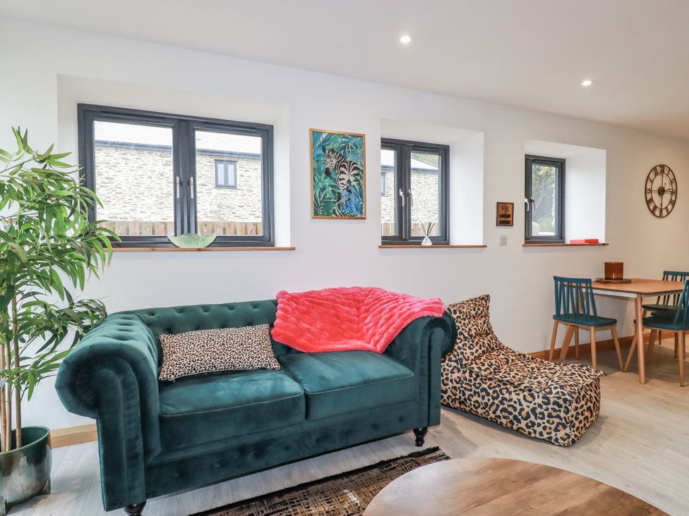 A living room with a green sofa and a dining table at Barn 2 