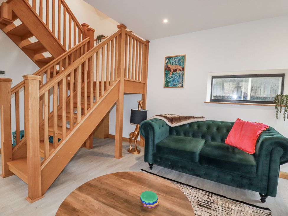 A living room with a green sofa and wooden stairs at Barn 2