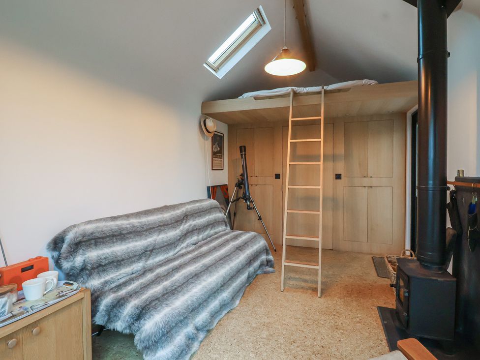A room with a sofa, ladder and telescope at The Bothy 