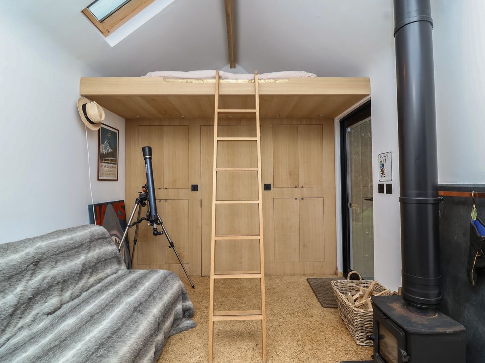 A loft bed with a ladder and telescope in a room at The Bothy