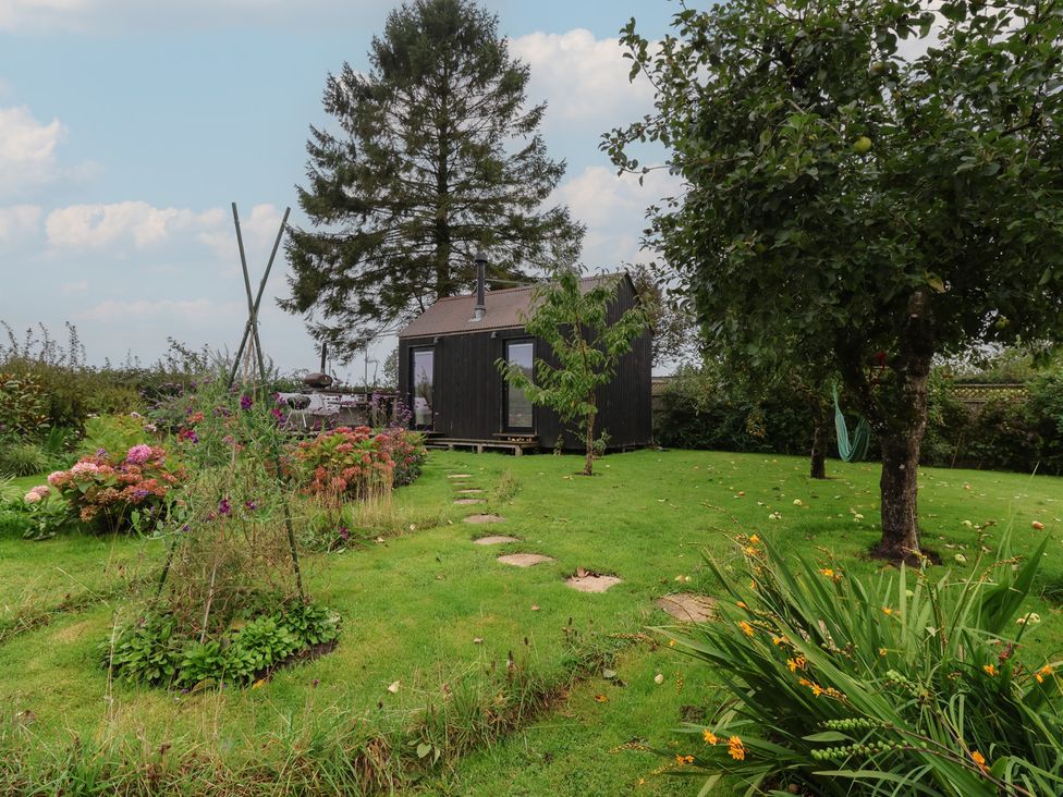 A garden with a shed and flowerbed at The Bothy in 