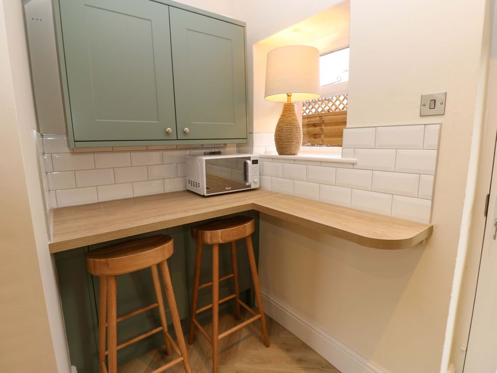 A kitchen with a microwave and bar stools at Milford in Great Corby, Wetheral