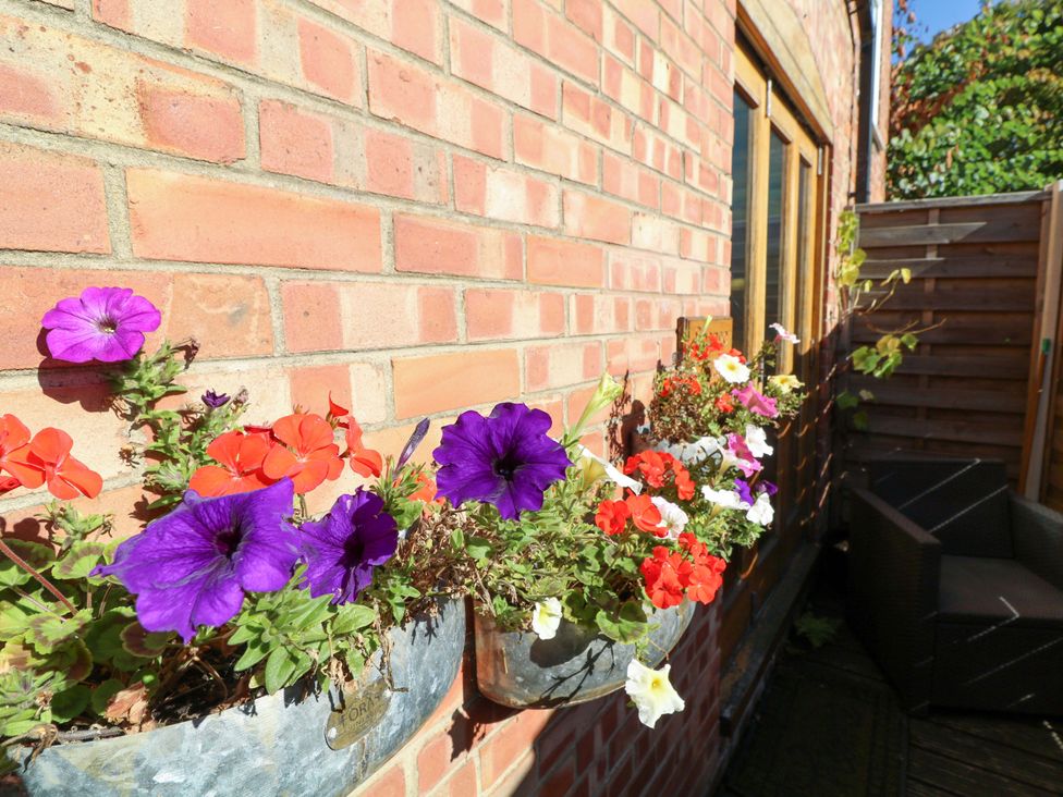A garden with flowers in planters beside a brick wall at 6 Brook Court Thulston near Derby