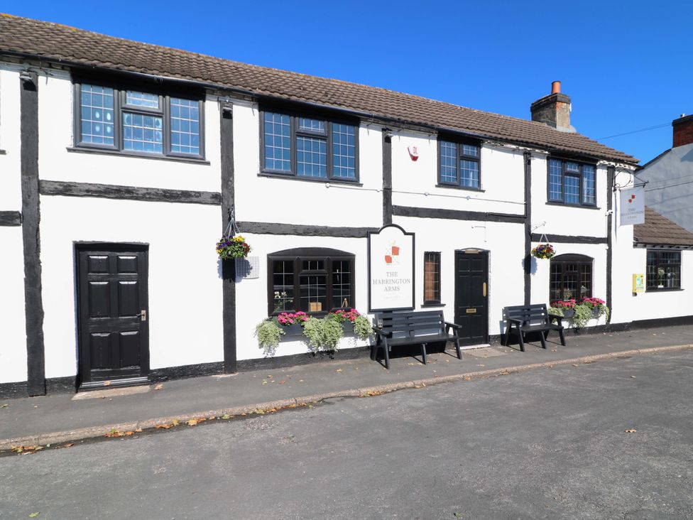 Exterior view of The Harrington Arms with benches and flower pots in Thulston near Derby