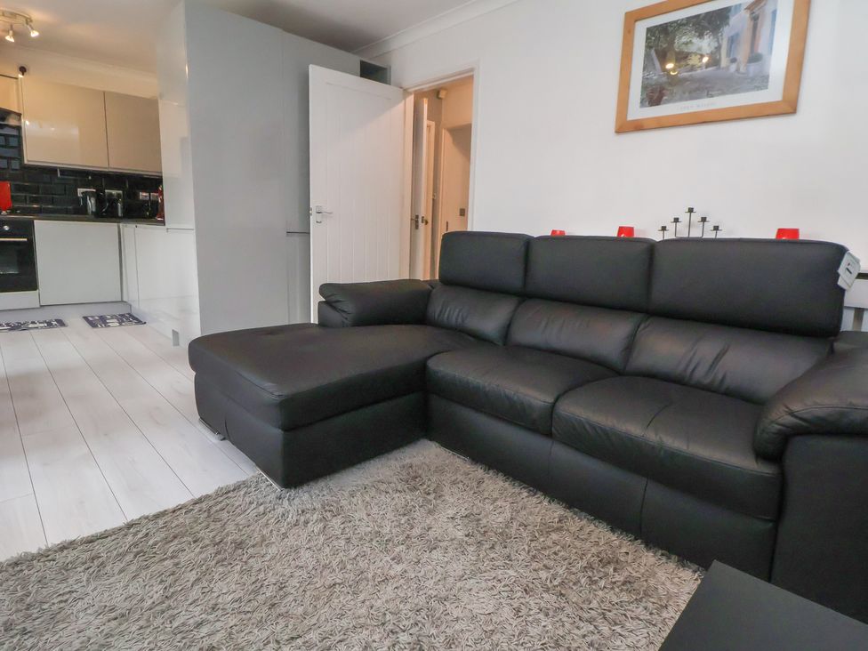 A living room with a sofa and a kitchen area at Flat 12 in Wallasey