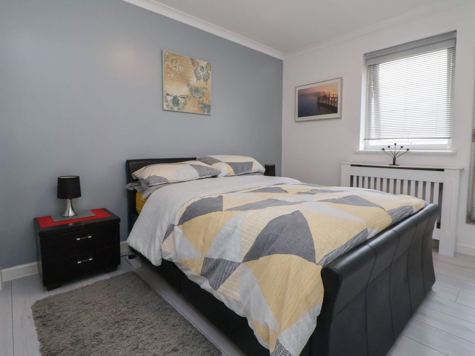 A bedroom with a bed and nightstand at Flat 12 Wallasey