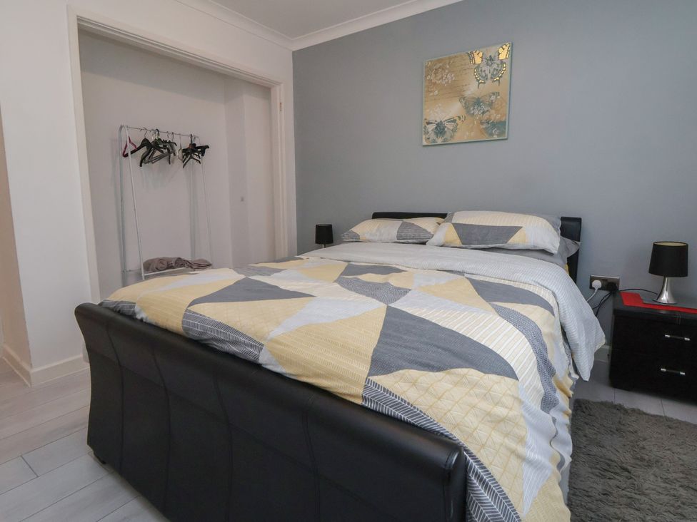 A bedroom with a bed and a bedside table at Flat 12 Wallasey