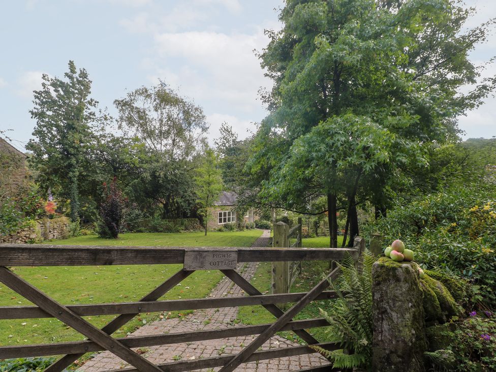 A gate leading to a pathway with trees and a cottage at Pigwig Cottage