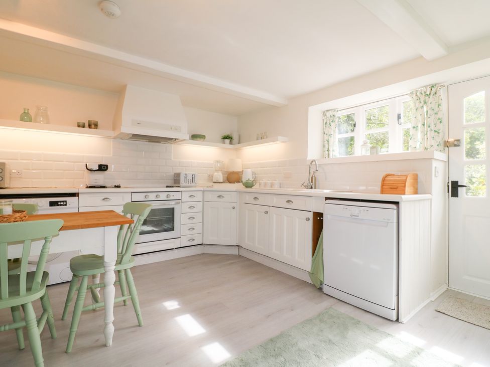 A kitchen with appliances and a table at Pigwig Cottage