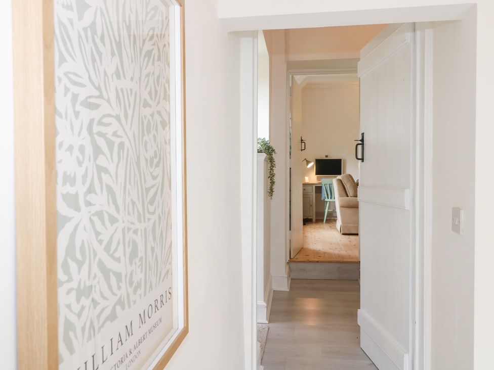 A hallway with a plant and a frame leading to a room with a desk at Pigwig Cottage