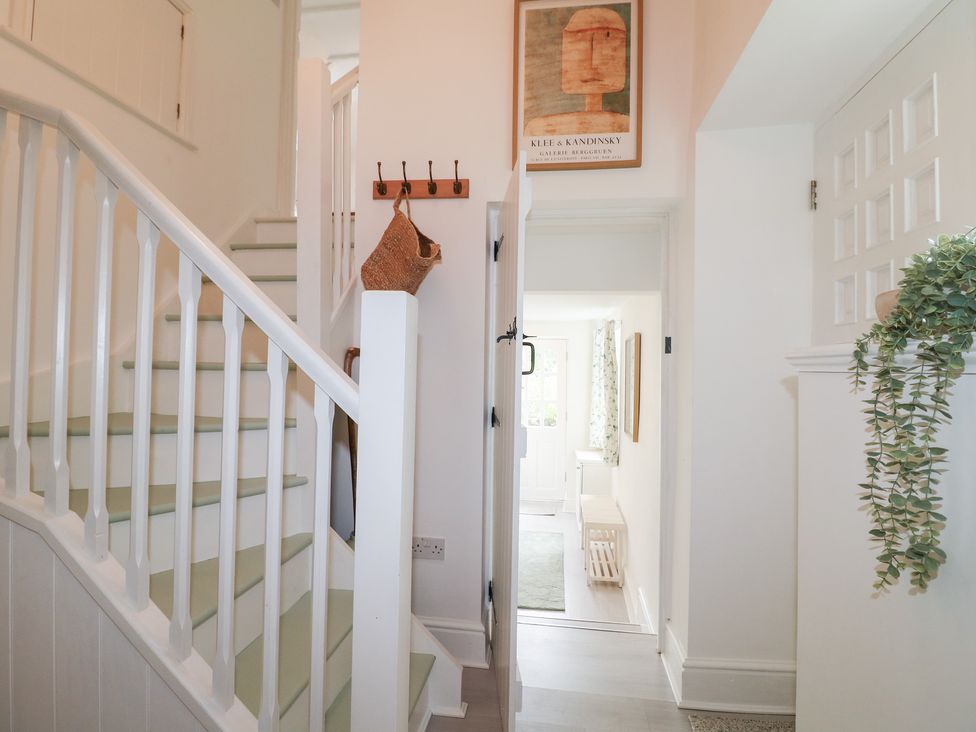 A hallway with a staircase and door at Pigwig Cottage