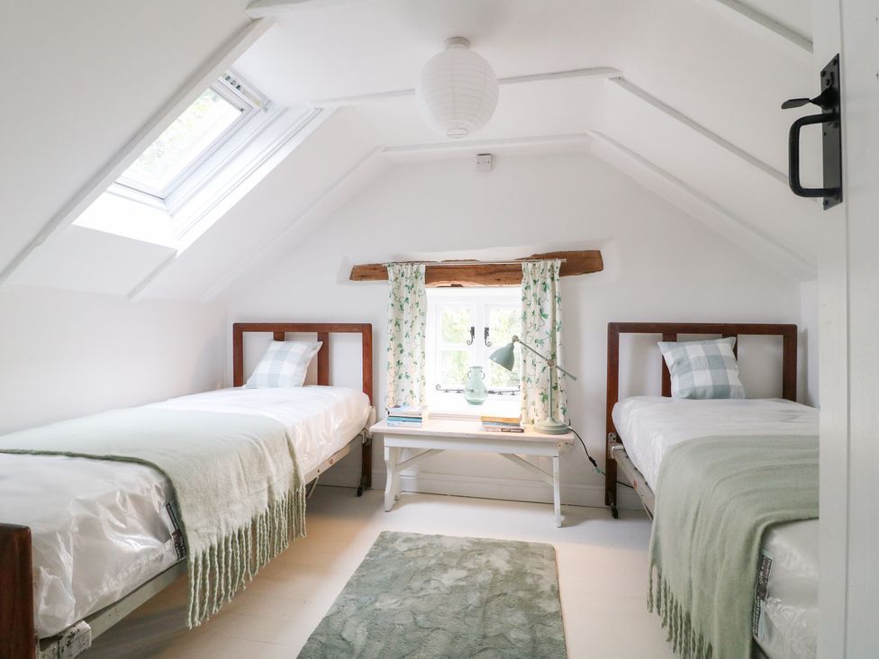 A bedroom with two beds and a window at Pigwig Cottage