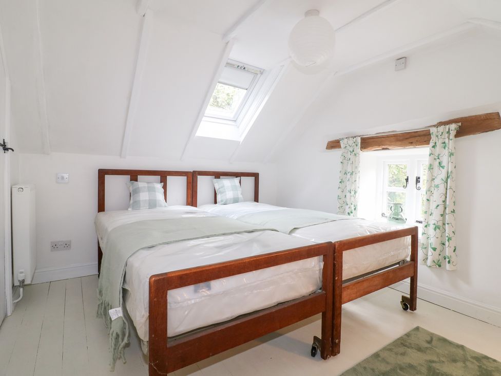 A bedroom with twin beds and a window at Pigwig Cottage
