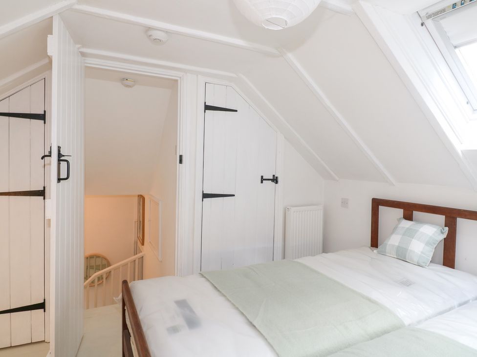 A bedroom with a bed and door leading to a staircase at Pigwig Cottage
