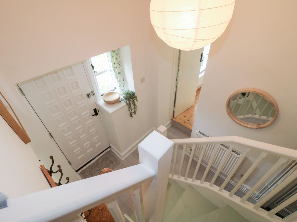 A hallway with stairs and a front door at Pigwig Cottage