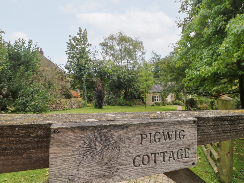 A garden with a wooden sign at Pigwig Cottage in 