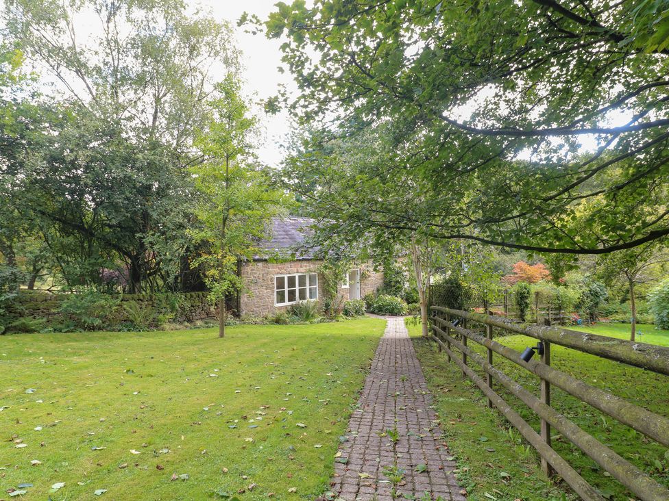 A house with a pathway leading to it surrounded by trees at Pigwig Cottage