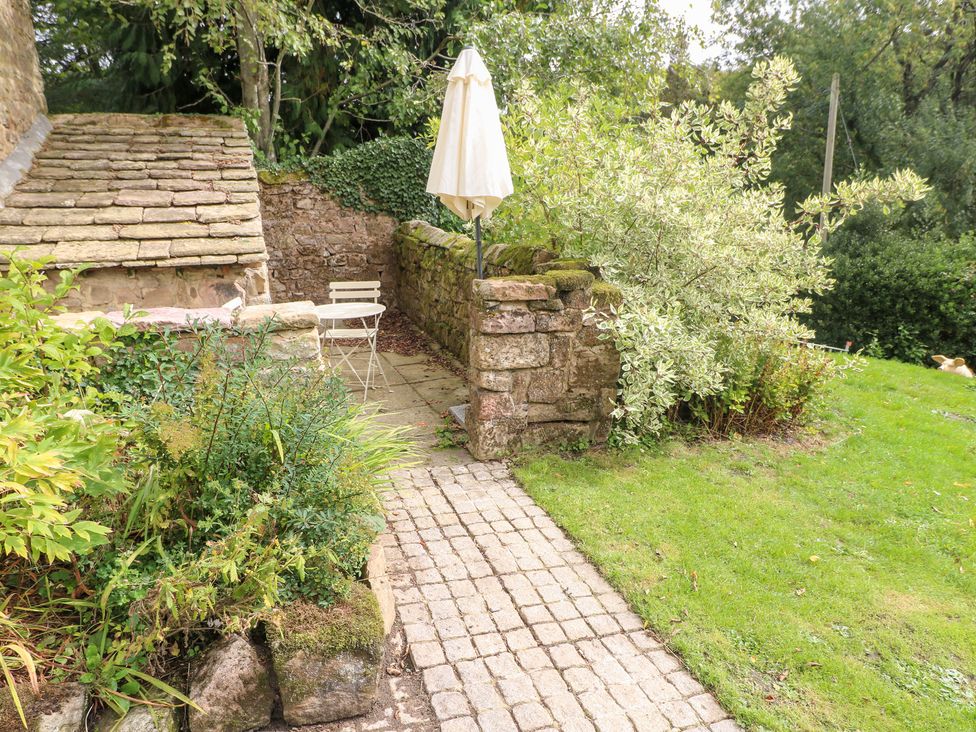 A garden area with a small table and chair next to a stone wall at Pigwig Cottage