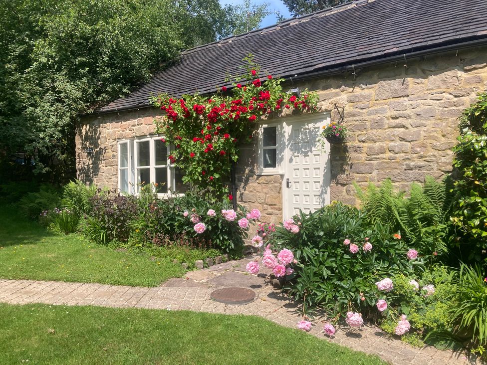 An outdoor area with a stone wall and flowers at Pigwig Cottage Longway Bank near Crich