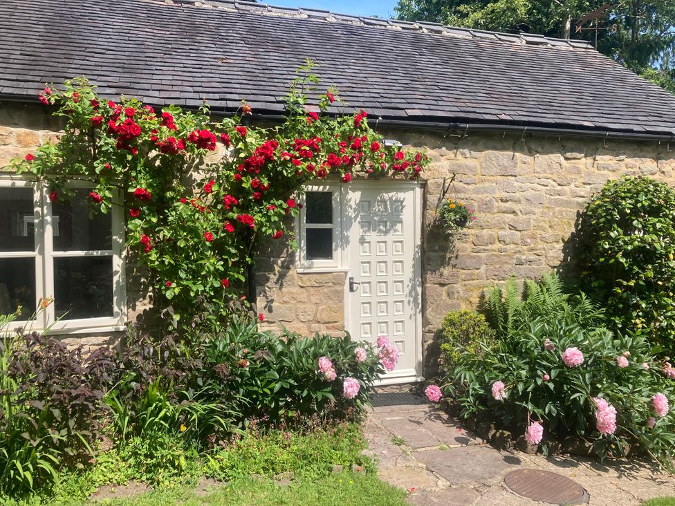 A stone cottage entrance with flowers and a pathway at Pigwig Cottage in Longway Bank near Crich
