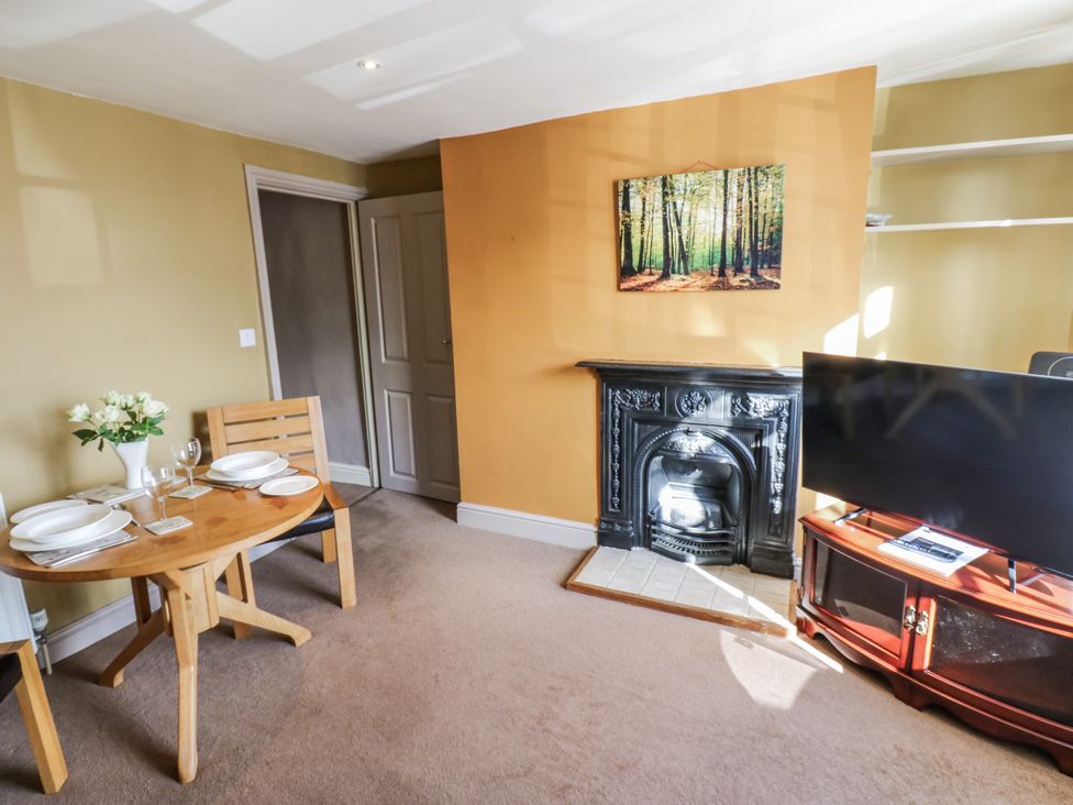 A living room with a dining table and a television at Ewe Cottage in Ripon