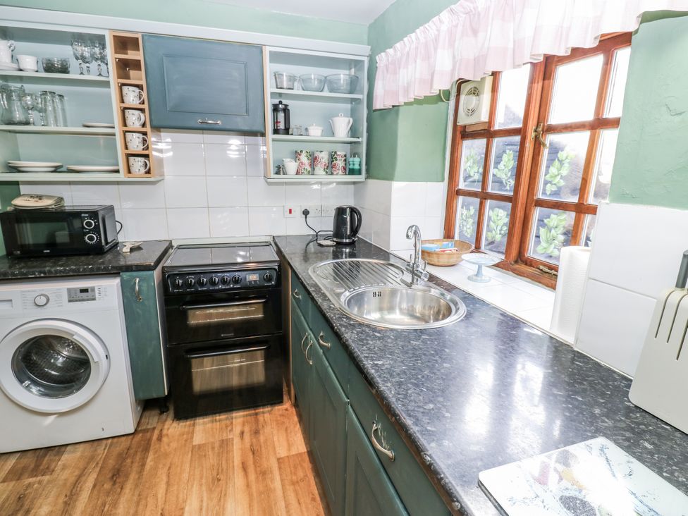 A kitchen with various appliances and shelves at Ewe Cottage in Ripon