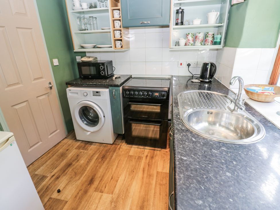 A kitchen with appliances including a washing machine and microwave at Ewe Cottage in Ripon
