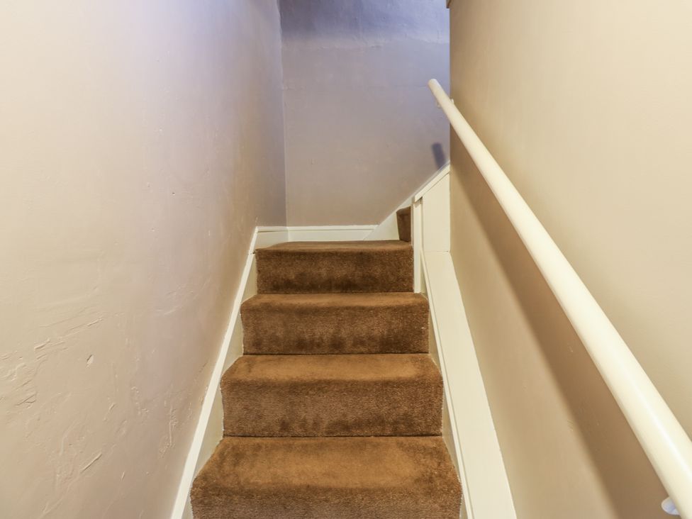 A staircase with carpeted steps and a handrail at Ewe Cottage in Ripon