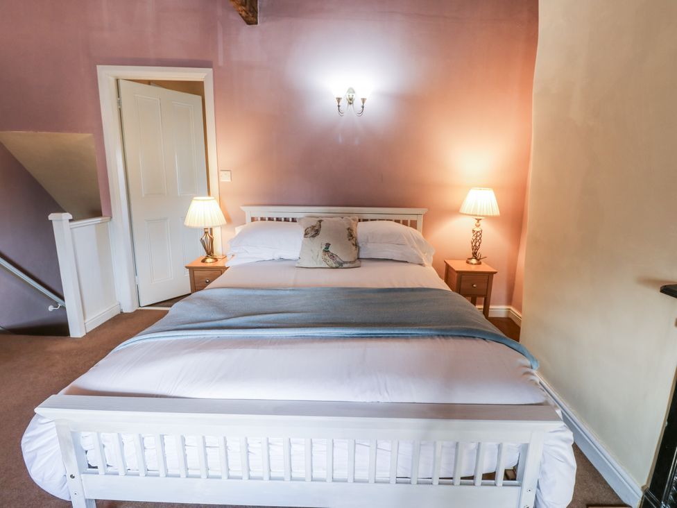 A bedroom with a bed and two nightstands at Ewe Cottage in Ripon