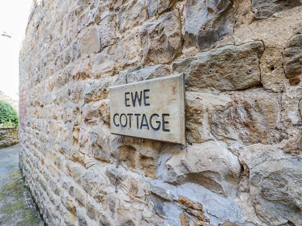 A sign for Ewe Cottage on a stone wall in Ripon