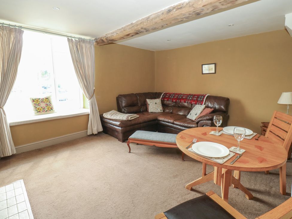 A living room with a sofa and dining table at Ewe Cottage in Masham